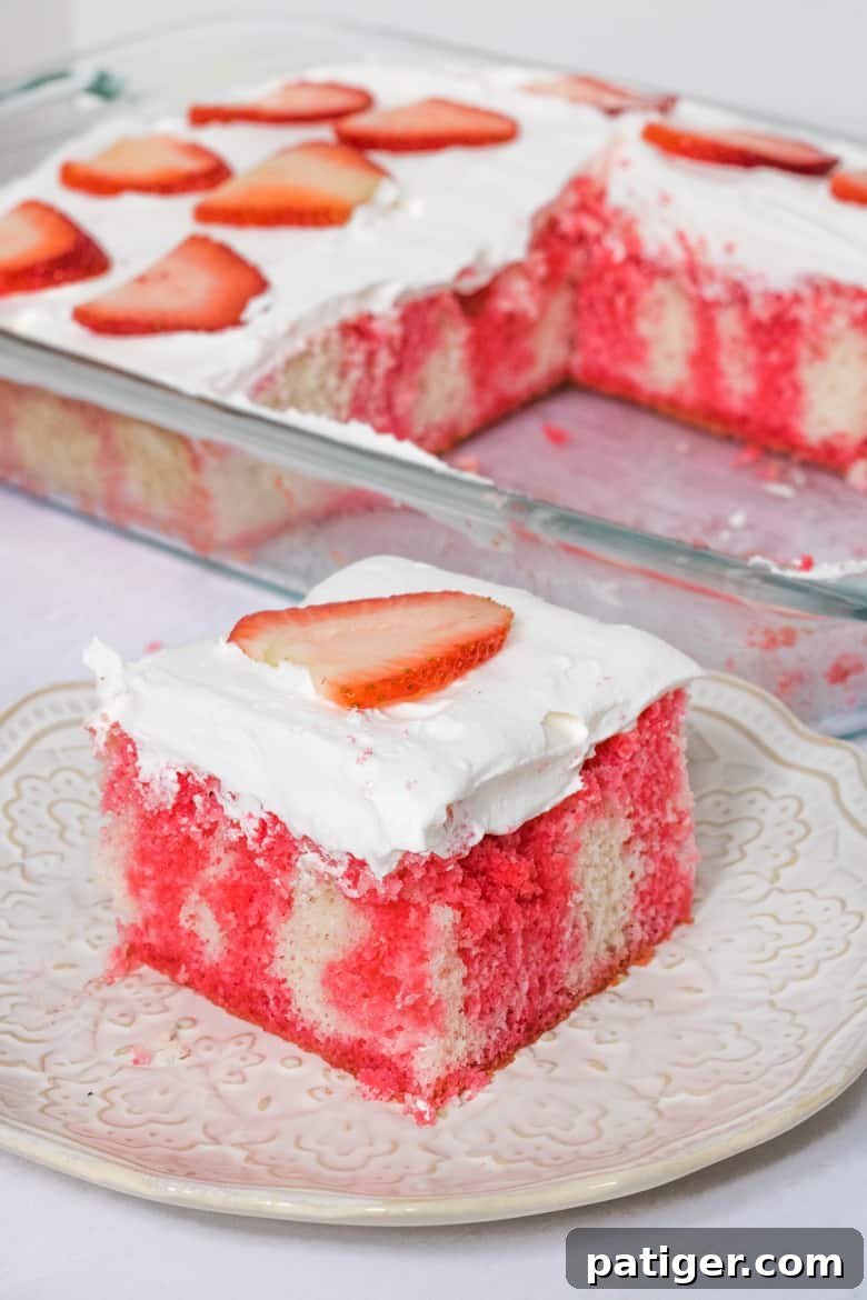 Strawberry Infusion Poke Cake 12 A beautifully decorated strawberry jello poke cake made with vanilla cake, creamy Cool Whip frosting, and garnished with fresh sliced berries, ready to be served.
