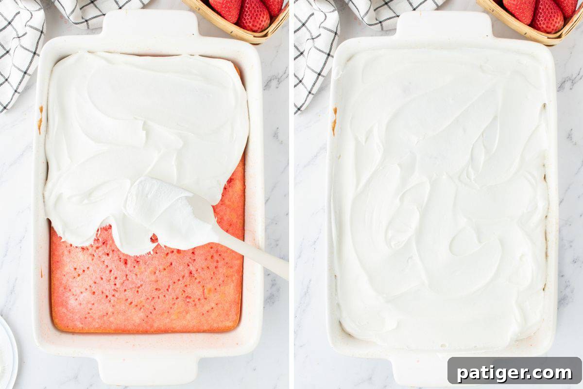 Strawberry Infusion Poke Cake 6 A finished strawberry Jello poke cake in a baking dish, generously topped with a layer of fluffy Cool Whip whipped topping.