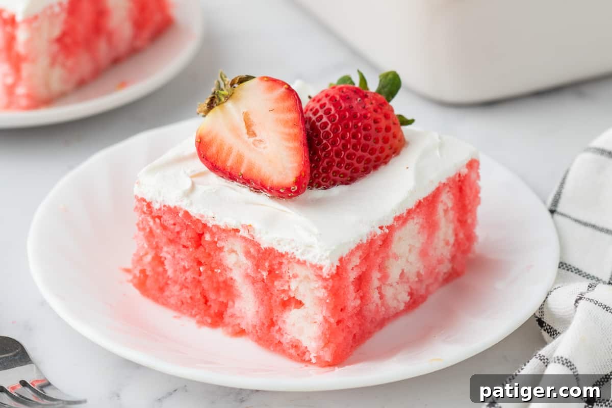 Strawberry Infusion Poke Cake 9 A stunning full view of a strawberry jello poke cake with a thick layer of Cool Whip and garnished with fresh strawberries.