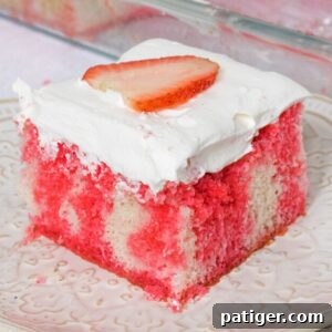 Strawberry Infusion Poke Cake 10 Square slice of strawberry jello poke cake made from white cake with red Jello drips through it. The cake is topped with cool whip topping and a slice of strawberry.