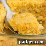 Serving spoon scooping cornbread casserole with jiffy mix and creamed corn.