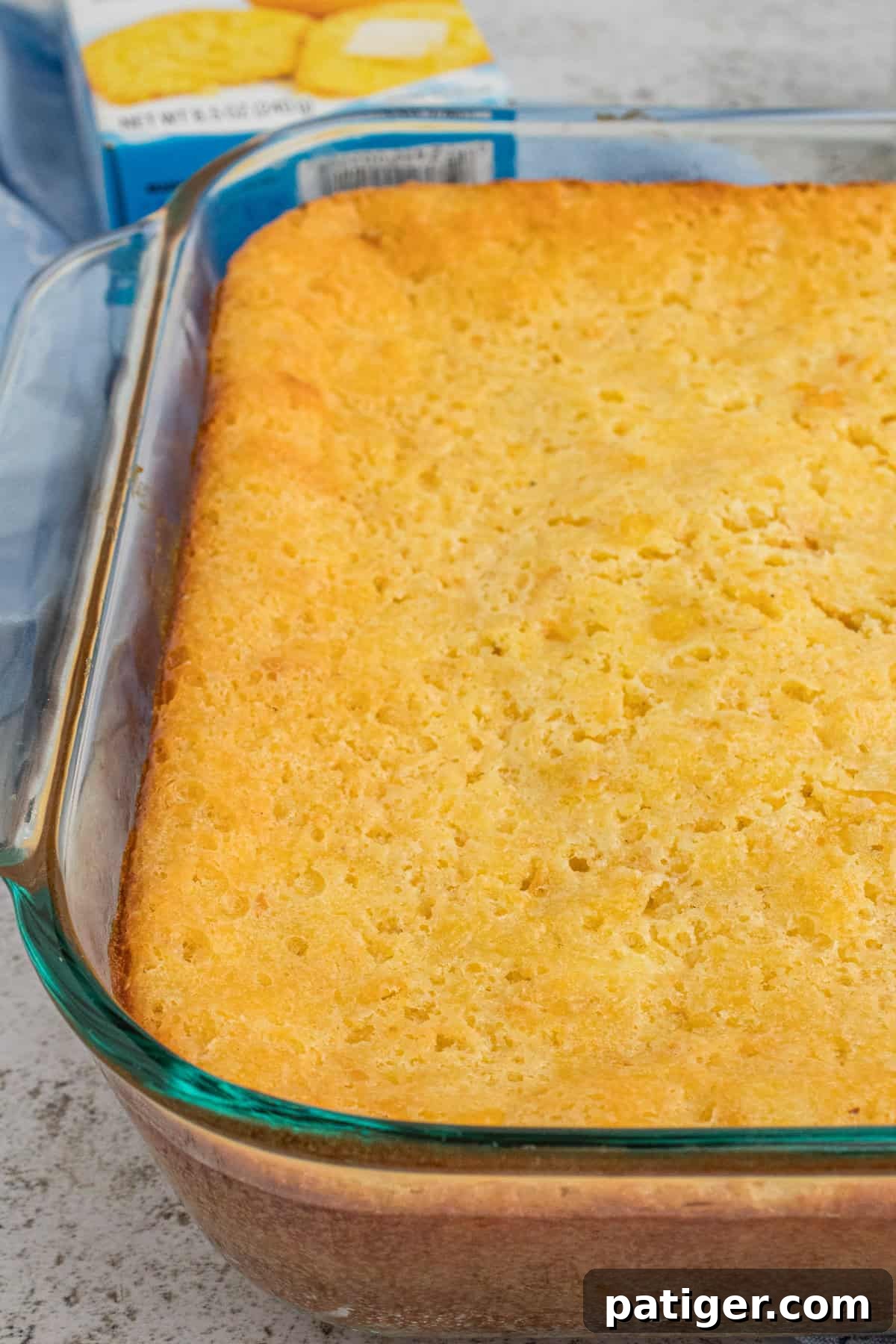 Golden Jiffy Cornbread and Creamed Corn Bake 9 A freshly baked Jiffy cornbread casserole, with a golden-brown top and slightly crisp edges, still in its glass baking pan.