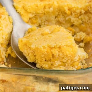 Serving spoon scooping cornbread casserole with jiffy mix and creamed corn.