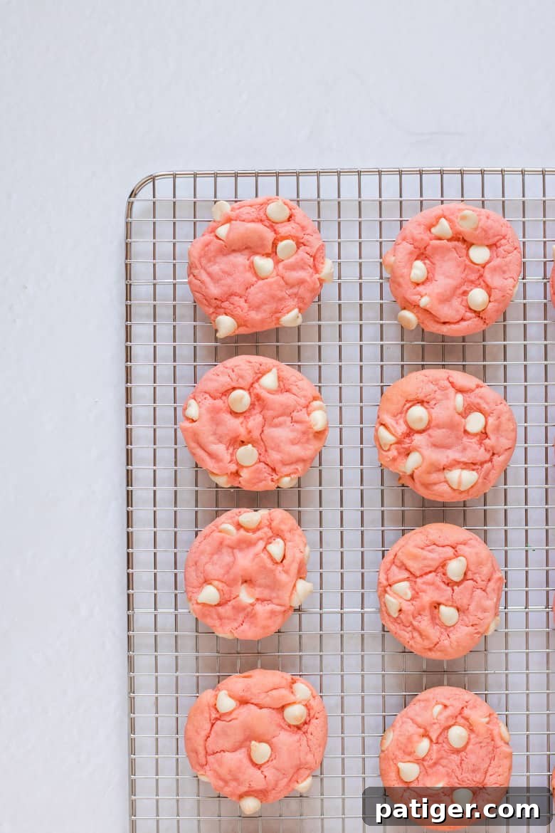 Freshly baked Strawberry Cake Mix Cookies with White Chocolate Chips cooling on a wire rack.