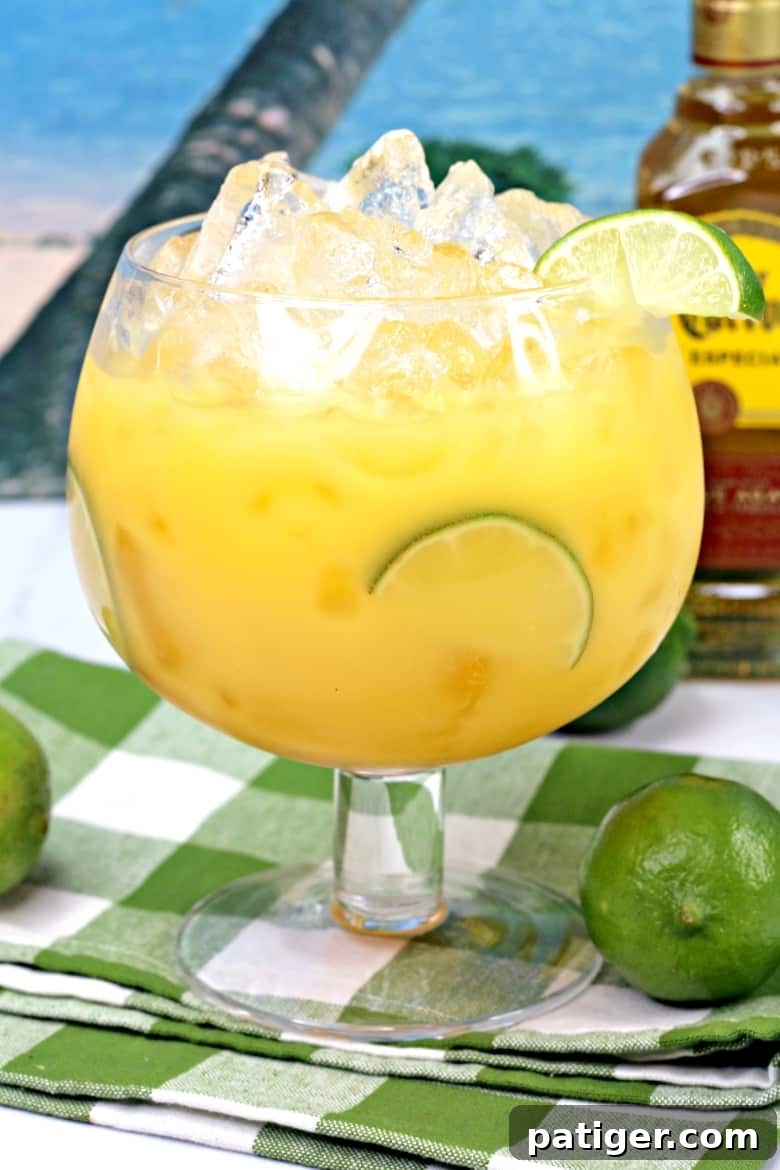 Tropical Hawaiian Margarita cocktail garnished with lime, with a bottle of tequila in the background