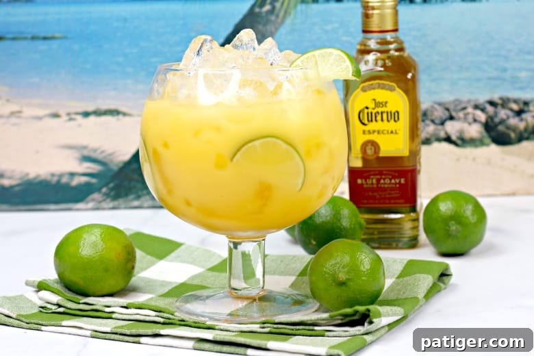 Hawaiian Margarita Cocktail with a bottle of Jose Cuervo tequila and fresh limes in the background, set for a refreshing summer drink
