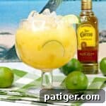 Hawaiian Margarita Cocktail with bottle of Jose Cuervo tequila and limes in background