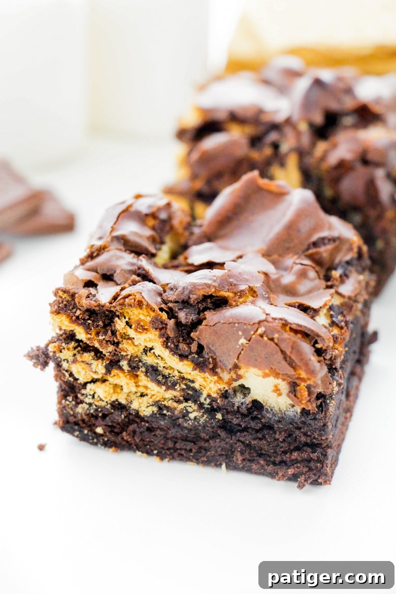 Campfire Smores Brownies 6 Close-up of a single S'mores Brownie square on a white plate, showing the rich chocolate, gooey marshmallows, and graham cracker pieces.