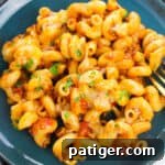 blue dinner plate with cheesy enchilada pasta topped with melted cheese and fresh cilantro