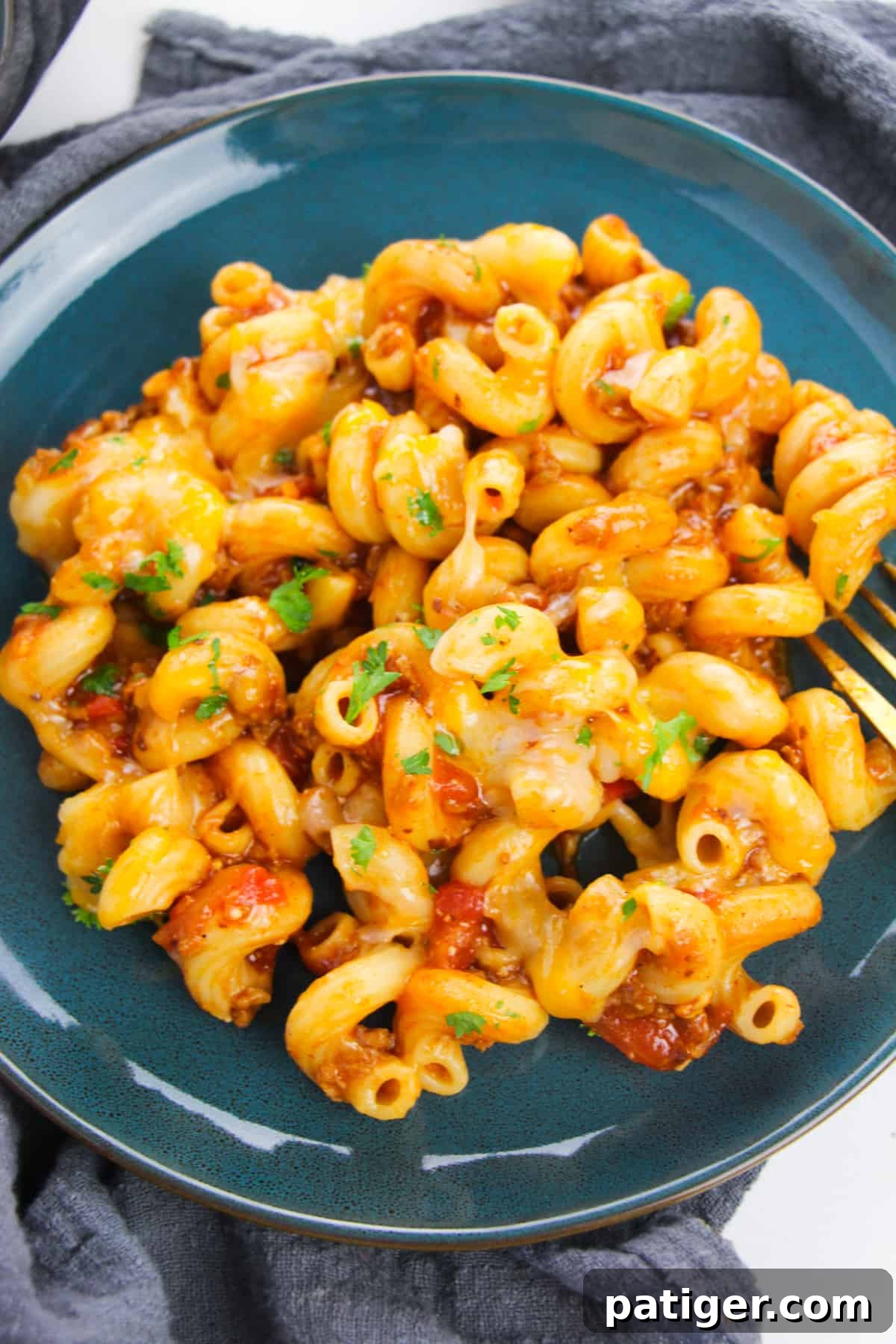 blue dinner plate with cheesy enchilada pasta topped with melted cheese and fresh cilantro