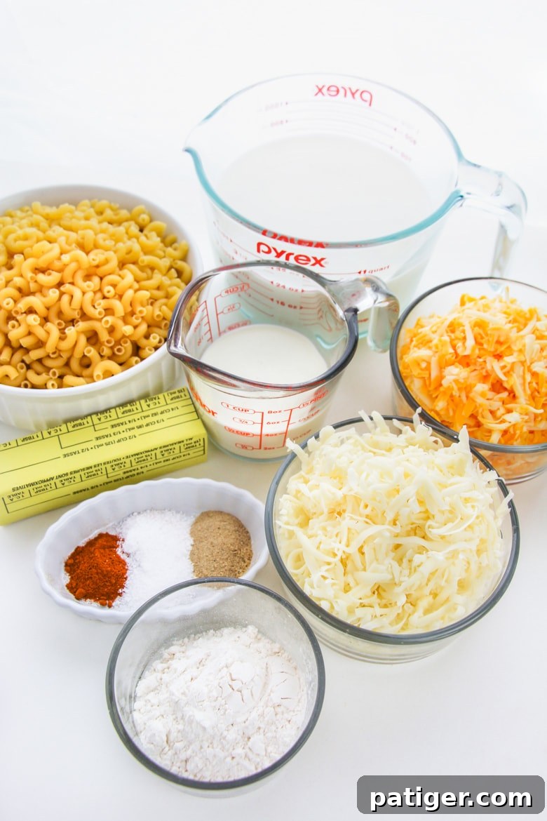 Ingredients laid out for baked mac and cheese: elbow pasta, milk, cheese blocks, butter, seasoning, flour, and heavy cream