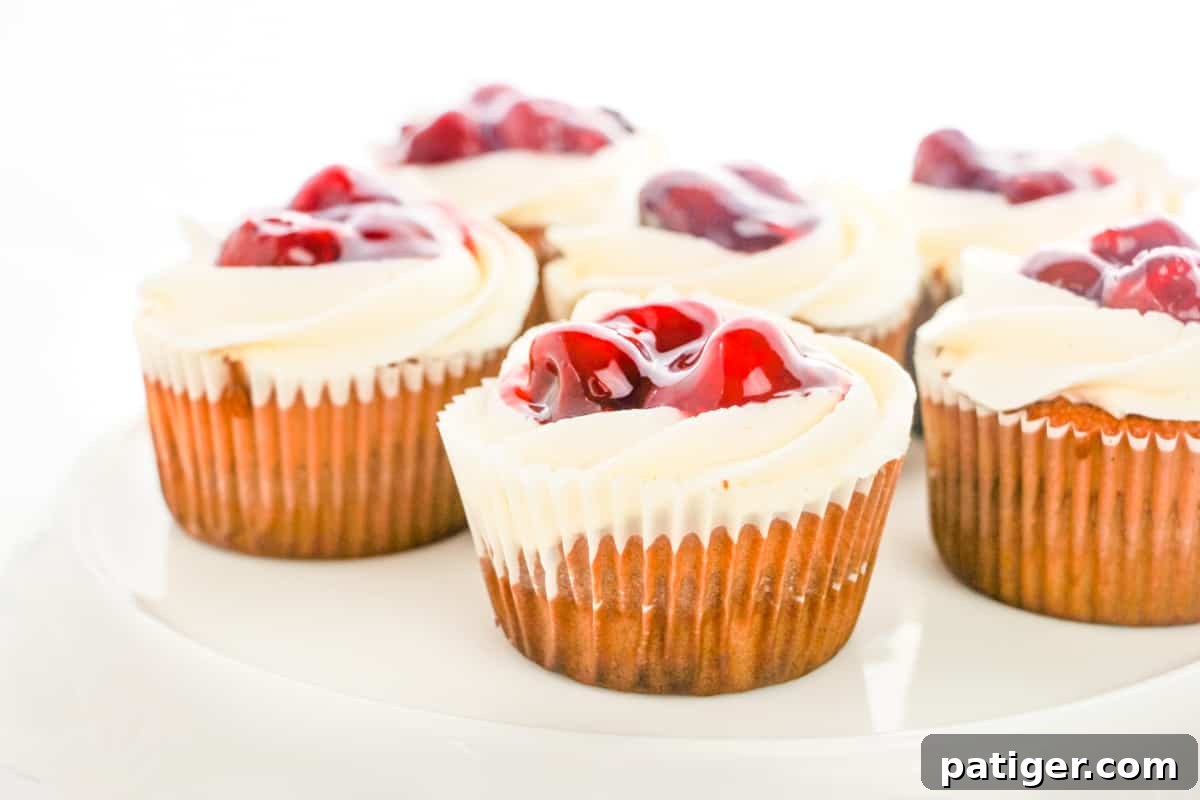 Delicious vanilla cupcakes elegantly topped with vibrant cherry pie filling and rich buttercream frosting