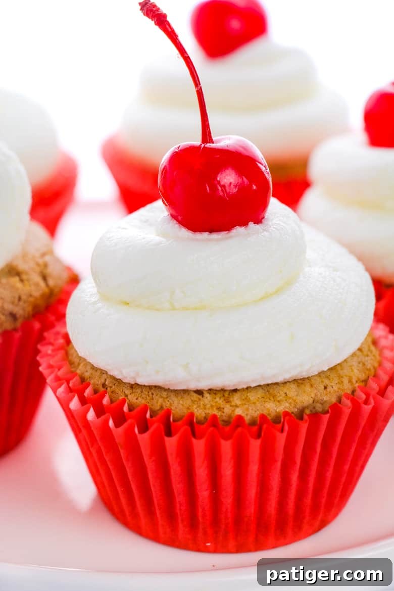 Root Beer Cupcakes in red liners topped with cherries and frosting