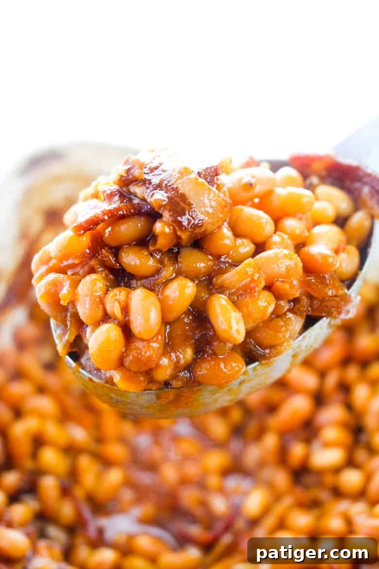 Ultimate Boston Baked Beans 3 Serving spoon scooping out beans and bacon.