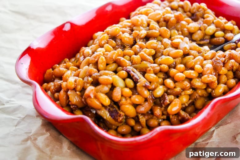 Ultimate Boston Baked Beans 10 Baked beans with chunks of bacon in red dish.