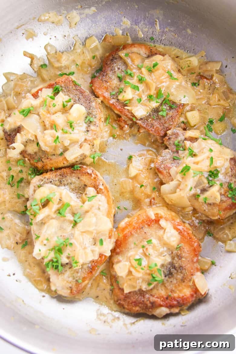 Skillet Pork Chop Recipe - A close-up view of the savory gravy bubbling around the pork chops in the skillet.