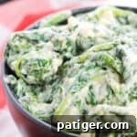 Creamed spinach with a creamy white sauce in a black bowl