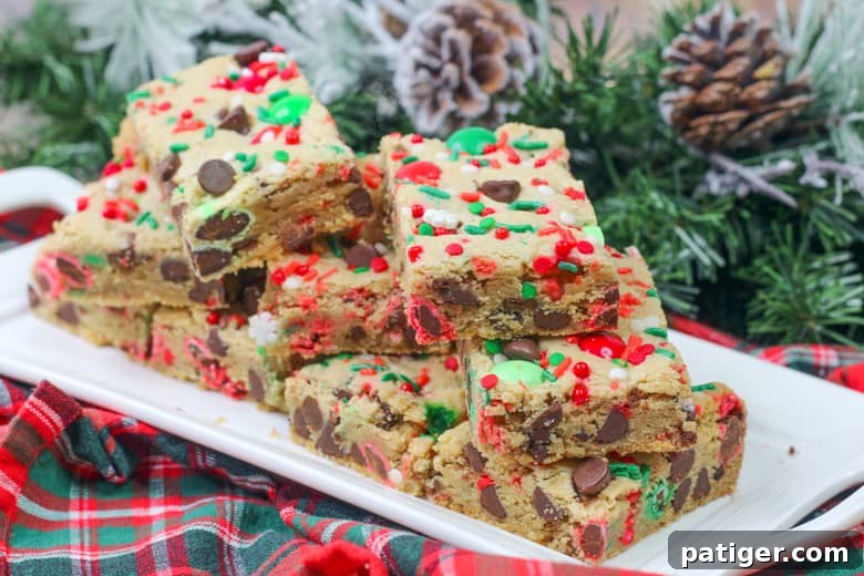 Holiday Cookie Bar Delights 3 Stacked Christmas Chocolate Chip Cookie Bars featuring vibrant red and green M&M's and sprinkles on a festive white plate, ready for serving.