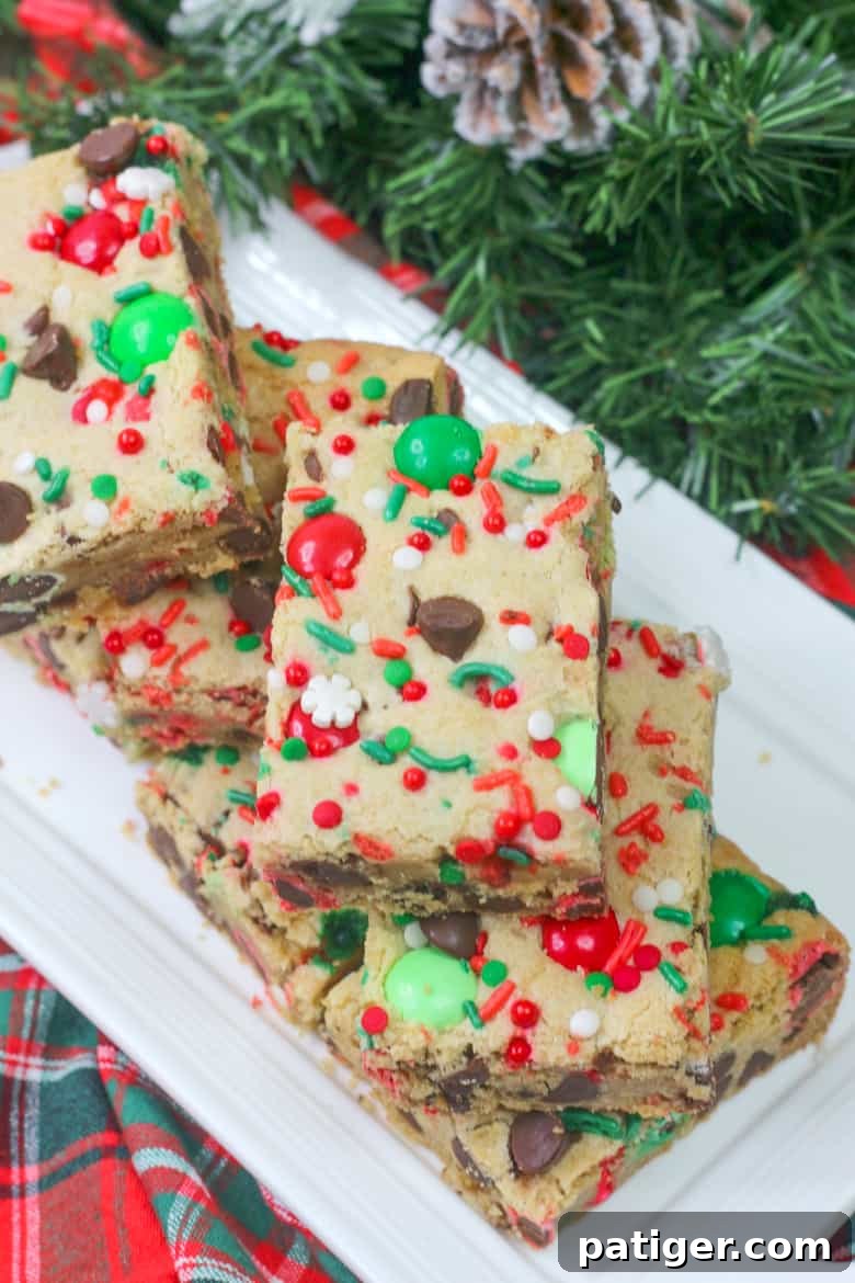 Holiday Cookie Bar Delights 4 Overhead close-up view of vibrant M&M Holiday Cookie Bars, generously topped with an assortment of festive sprinkles, showcasing their irresistible texture.