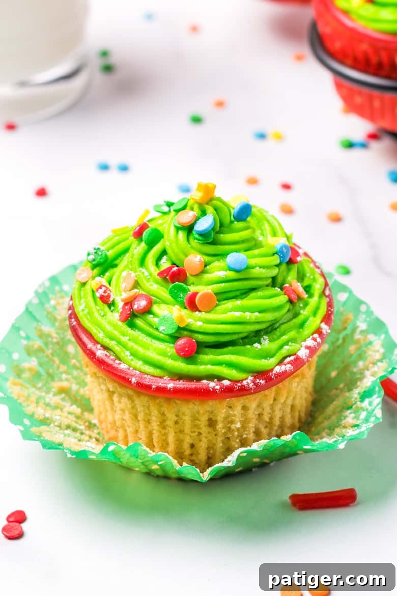 Cupcake with green frosting and rainbow sprinkles, decorated as a Christmas tree