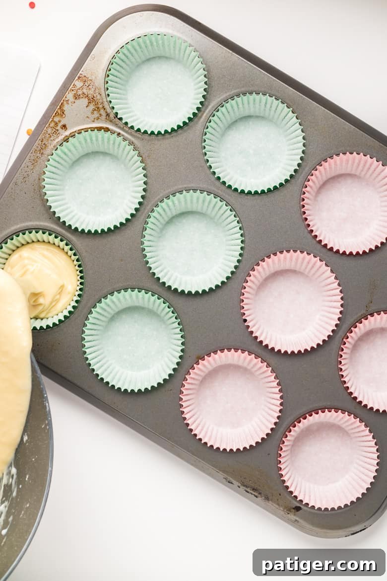 Pouring cupcake batter into a lined cupcake tin