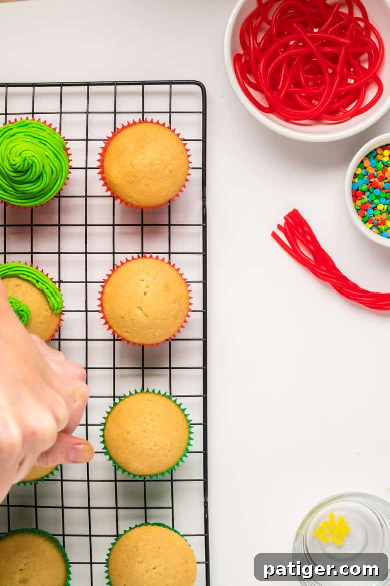 Hand piping green icing onto vanilla cupcakes