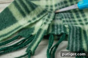 Charming Wooden Block Snowmen 7 Green plaid scarf being cut into strips with scissors