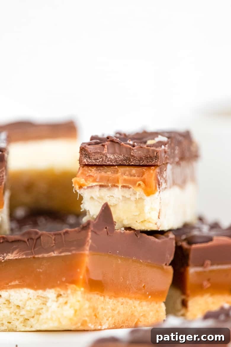 Homemade Twix Bars, also known as Millionaire Bars, showcasing perfectly defined layers of golden shortbread, rich caramel, and glossy chocolate.