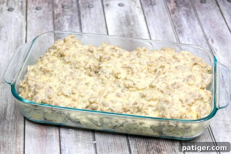 A casserole dish with the pre-baked biscuit layer topped with thick, creamy sausage gravy.