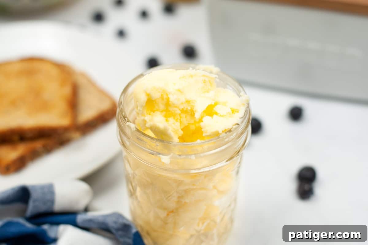 Jar of butter with toast and berries in background