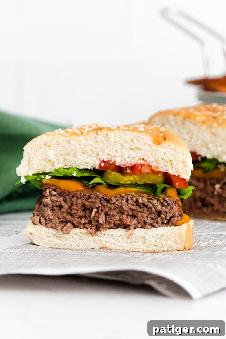 Thick and Juicy Air Fryer Hamburger with lettuce tomato and cheese cut in half