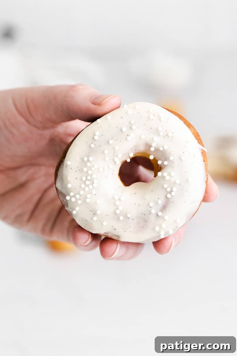 Homemade Air Fryer Doughnut Delights 3 A hand holding a homemade air fryer donut with sweet vanilla frosting, ready to be enjoyed.