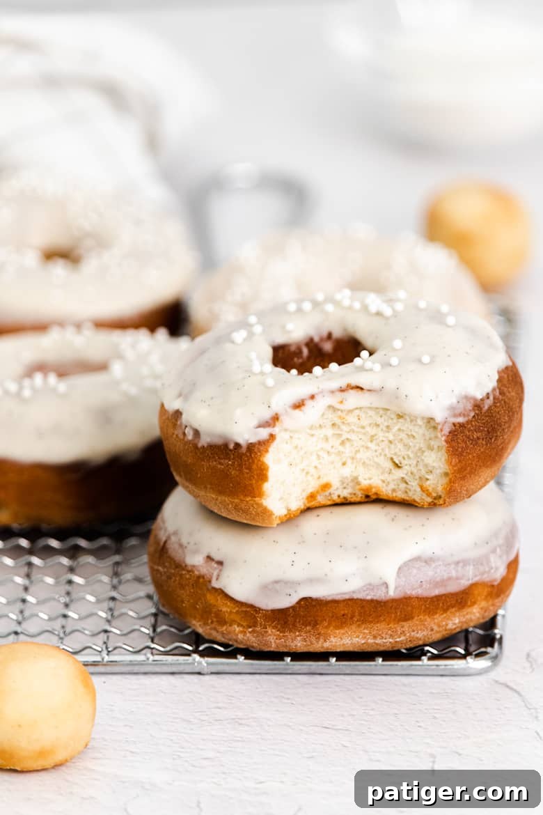 Homemade Air Fryer Doughnut Delights 4 Several homemade air fryer donuts with vanilla icing, one with a bite taken out of it to reveal its cake-like, fluffy interior.