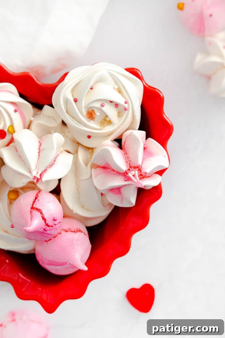 Pink and white meringues decorated with Valentine's Day sprinkles and in a red heart bowl, highlighting easy Valentine's Day baking
