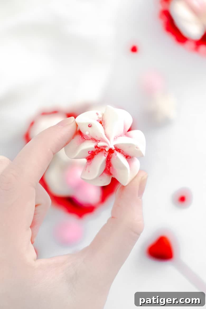 Hand holding a valentine's day meringue cookie, emphasizing the light and delicate texture