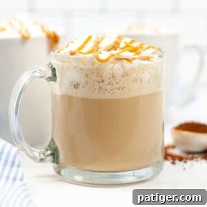 Caramel Macchiato topped with whipped cream and a drizzle of caramel in glass mug