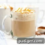 Caramel Macchiato topped with whipped cream and a drizzle of caramel in glass mug