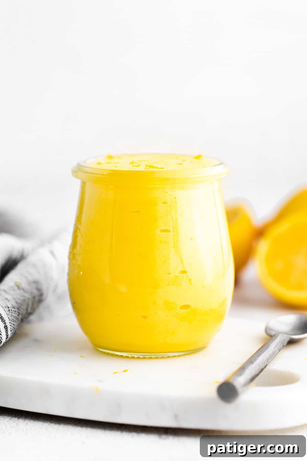 Jar of homemade lemon curd with fresh lemons in background