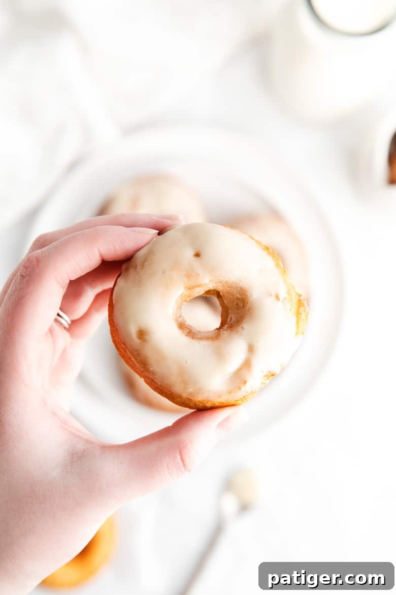 woman's hand holding glazed old-fashioned doughnut 
