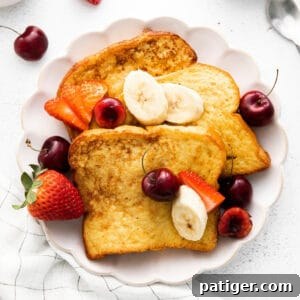 Three pieces of brioche french toast plated with banana slices and fresh berries