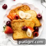 Three pieces of brioche french toast plated with banana slices and fresh berries