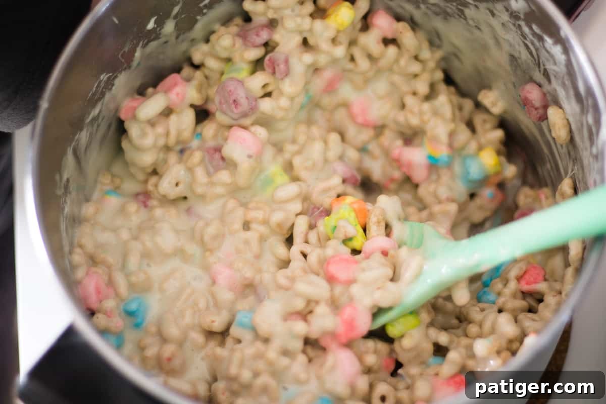 Magical Lucky Charms Treats 6 Lucky charms cereal being stirred into melted marshmallows in a large pot