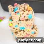 Magical Lucky Charms Treats 9 Three lucky charms marshmallow cereal bars cut into squares and stacked on top of one another on a white plate