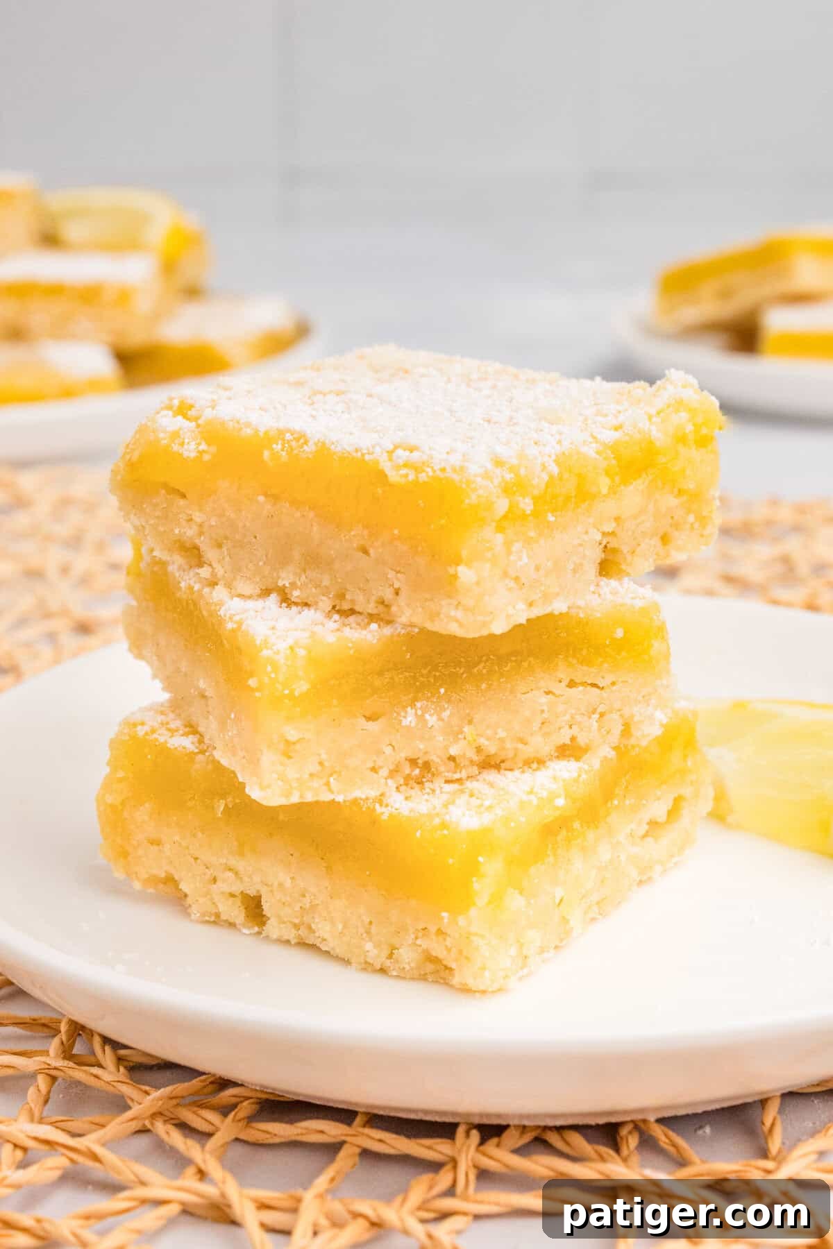 Stacked lemon shortbread bars on white plate.