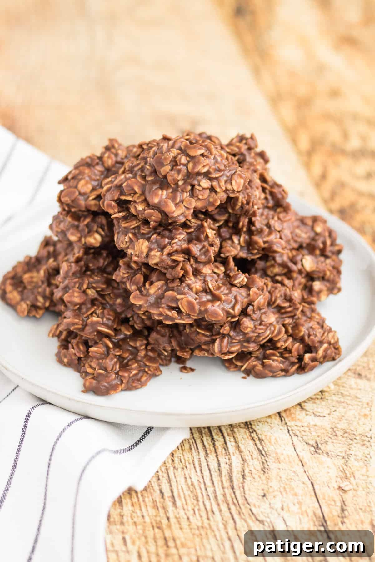 Old-fashioned no-bake chocolate peanut butter oatmeal cookies served on a white plate on a wooden table.