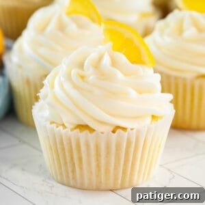Lemon cupcakes topped with cream cheese frosting and garnished with a slice of lemon