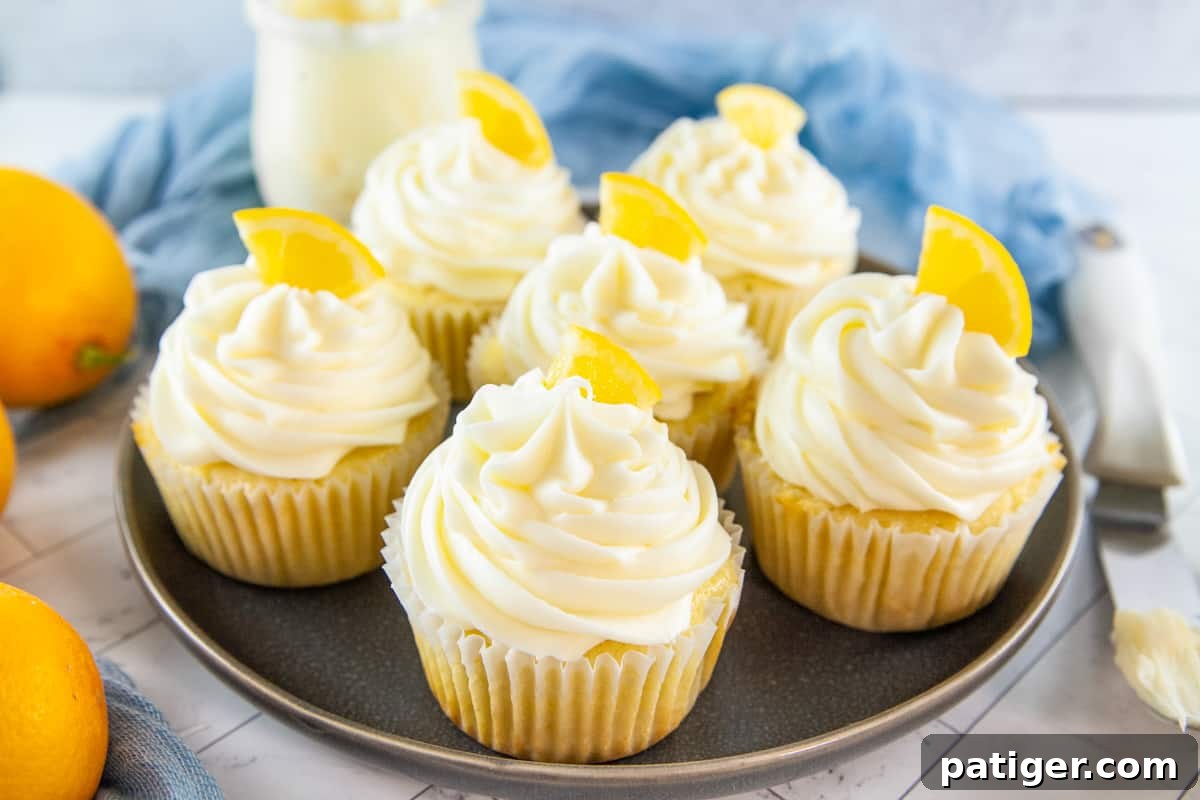 Six lemon cupcakes adorned with fluffy cream cheese icing and candied lemon wedges, ready to be enjoyed.