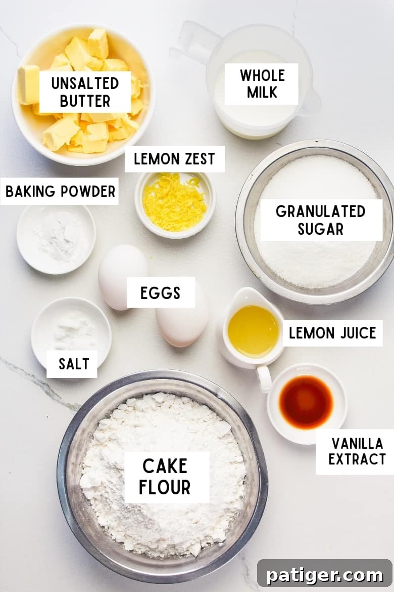 A flat lay of all ingredients for lemon cupcakes: unsalted butter, baking powder, milk, lemon zest, granulated sugar, eggs, salt, lemon juice, cake flour, vanilla extract arranged on a wooden surface.