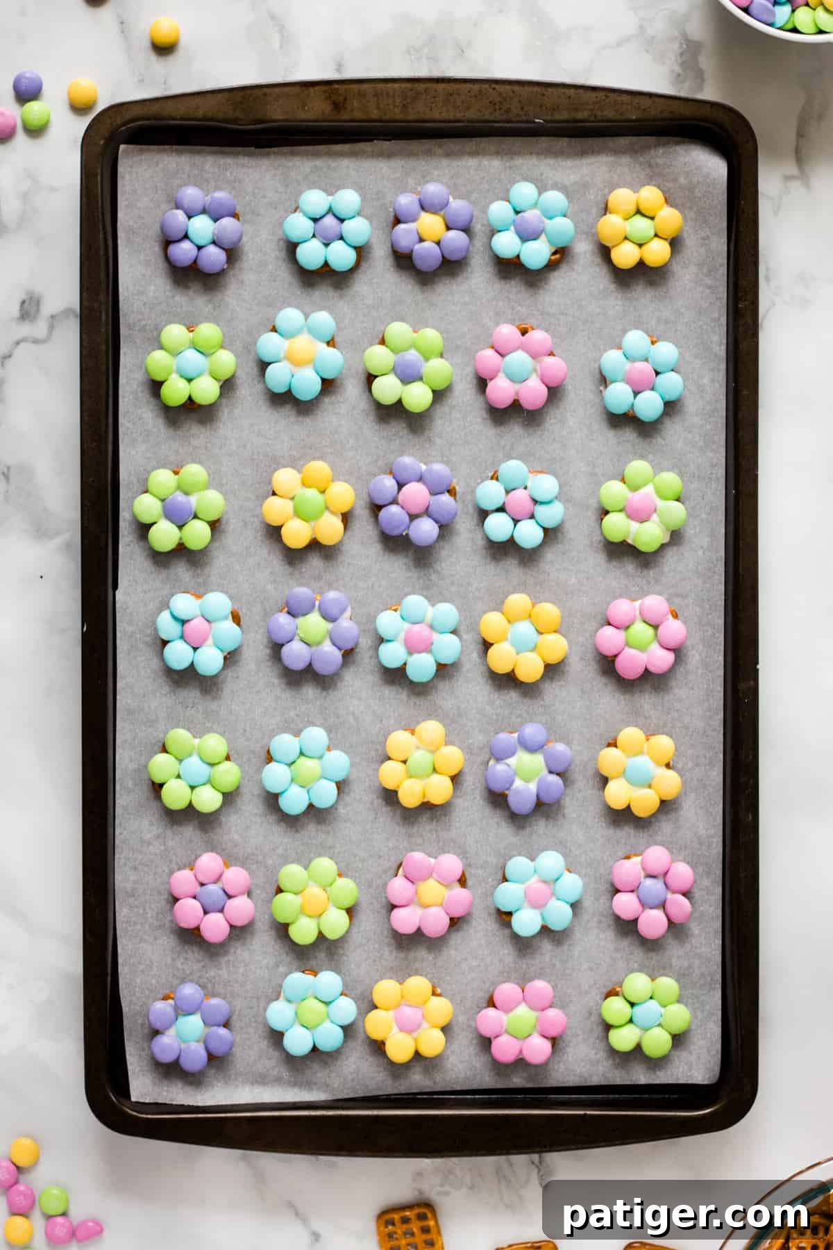 M&M Pretzel flower bites arranged in even rows on lined baking sheet