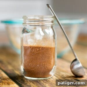 homemade apple pie spice in a small mason jar with small scoop next to it